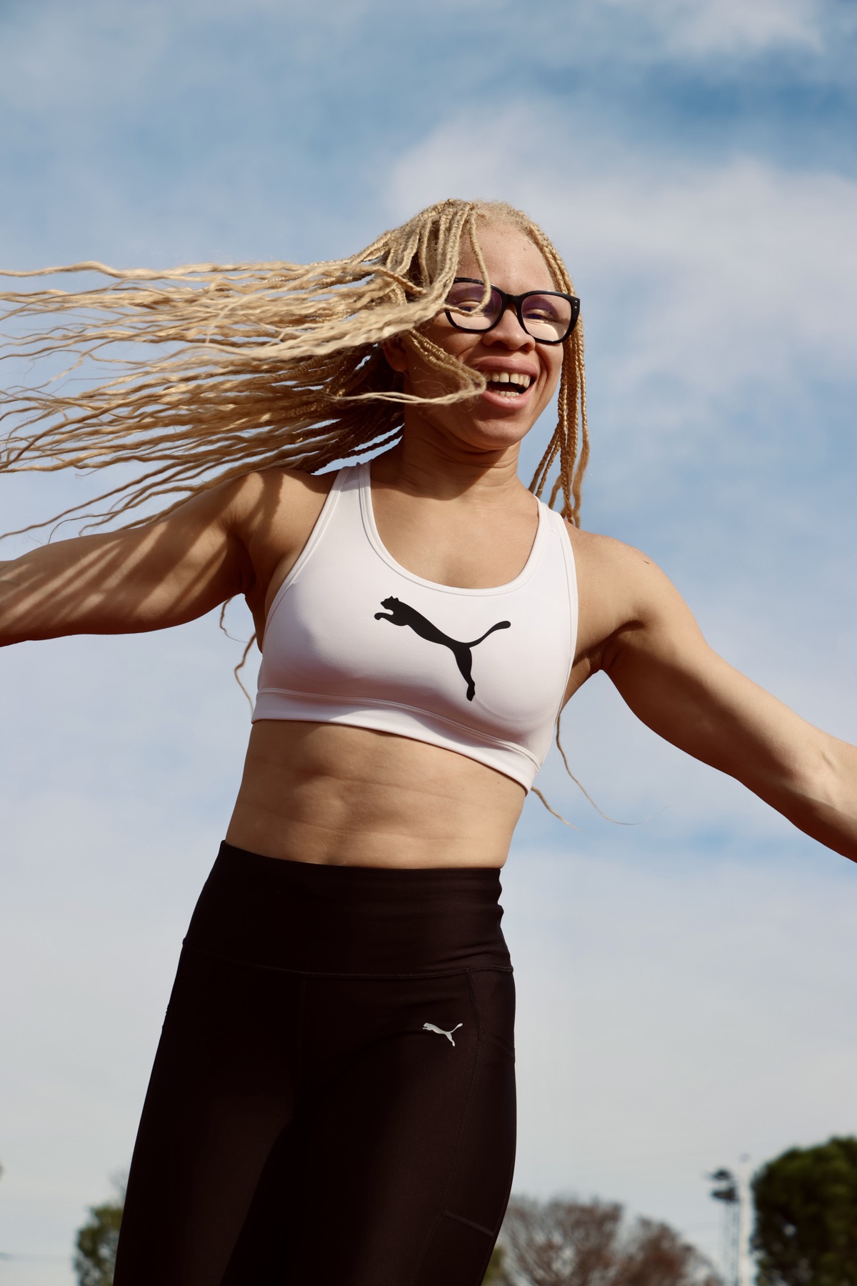 Adi Iglesias sonriendo con un top blanco y las trenzas al viento.